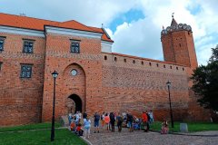 Grupa turystów na tle Muzeum Zamku Królewskiego w Łęczycy.