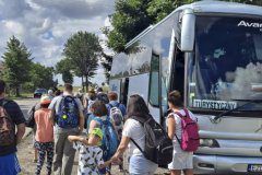 Liczna grupa uczestników wycieczki wsiada do autobusu