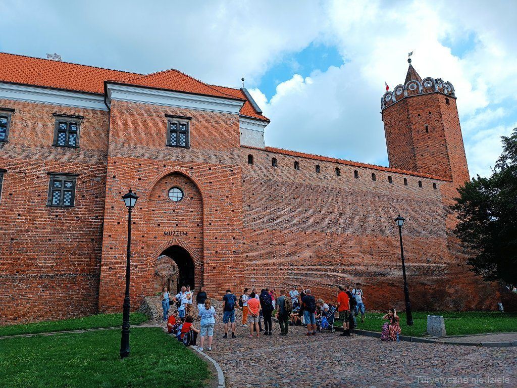 Grupa turystów na tle Muzeum Zamku Królewskiego w Łęczycy.