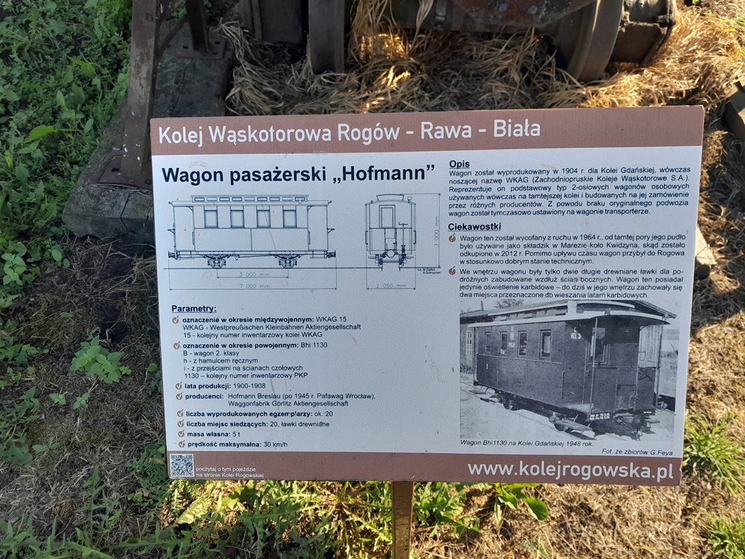 Tabliczka informująca o trasie kolei wąskotorowej na trasie Rogów – Rawa – Biała, wbita w trawnik